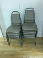 Stacked view of nine chairs showing dark tan vinyl seat and back cushions with metal frame, some wear and dirt visible