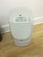 Front view of the white Whirlpool Gold dehumidifier sitting on a hardwood floor, showing front grill and general shape.