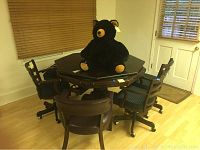 Game table in poker card mode with chairs around it and stuffed black bear on top