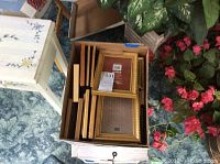 Top-down view of two boxes containing assorted wood and gold tone picture frames, mainly 5x7 size.