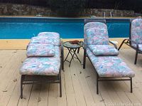 Two adjustable patio loungers with colorful patterned cushions beside a pool, showing overall condition and style
