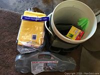 Photo of polishing cloths, bucket, tool kit case and other items on the floor.