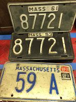 Three Massachusetts license plates stacked: 1961 black, 1953 black, 1971 cream with blue 59 A plate that has registration stickers