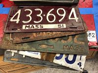 Pile of stacked vintage Massachusetts license plates showing front maroon 1951 plate with embossed white numbers '433·694'