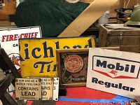 Overview of all five signs grouped on red surface including Coors, Mobil, Texaco, Richland and warning sign