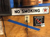 Two wall-mounted No Smoking signs mounted on plywood wall