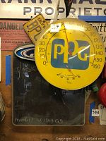 Front view of yellow round PPG thermometer with temperature scale, humidity gauge, and black marks visible on front surface.