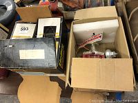Photo of two boxes on a table, one opened showing a red metal carburetor and foam packaging, the other closed.
