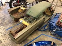 Overall view of metal 2-door car body shell on wood base