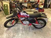 Right side profile of bike showing red frame, engine, tires