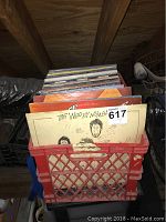 Red plastic crate filled with over 30 vinyl records, showing cover of The Who's 'By Numbers'.