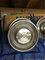 Five metal hub caps stacked showing concentric ridged design and Cadillac emblem on top cap.