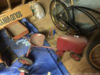Overhead view of red metal pedal tractor with attached cart on blue tarp