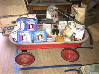 Red vintage kids wagon loaded with multiple limited edition Pokémon trading card boxes, unopened Beanie Babies, and various small collectibles.