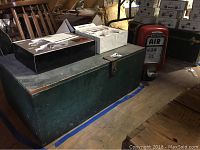 Front view of green wooden trunk with latch and items on top