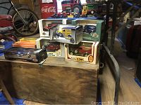 Wooden trunk with model cars on top including various collectible banks and scale models in original boxes.