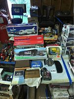 Wide view of assortment showing boxed model trucks, collectibles, and wooden boxes on a table.