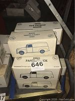 Photo of stacked white boxes containing 1950 Chevy Panel Bank and 1960 4x4 Pickup Bank model cars, showing labels and drawings of the vehicles