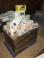 Photo of boxed collectible cars stacked on and around a wooden crate, showing product packaging and crate surface.