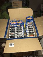 Box open showing multiple rows of Hot Wheels cars in blister packaging lined up inside a cardboard box.
