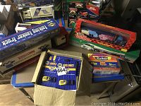 Overview of the unopened collectible cars and trucks in original packaging. Shows multiple brand boxes including NAPA Auto Parts, Racing Champions, and Micro Machines.