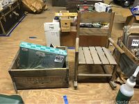 Wooden crate with baseball cards inside next to small vintage wooden rocking chair on wood floor
