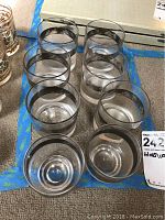 Eight clear glasses arranged in two rows, top view shows all glasses uniform with silver etched band near rim.