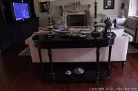 Front view of demi lune wood sofa table with one drawer and lower shelf, showing wear and scratches.