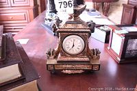 Front view showing the clock face with Roman numerals and ornate gold-tone decorative mantel clock.