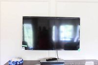 Front view of 46" Samsung flat screen TV mounted on wall above console