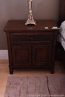 Front view of one nightstand showing top drawer and cabinet doors closed