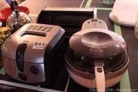 View showing T-Fal and PC brand digital deep fryers side by side on tabletop
