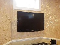 Samsung 40 inch flat-screen TV wall-mounted in a room with textured wallpaper and white trim, showing full view of the TV.