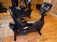 Side view of entire recumbent bike showing grey frame, black seat, pedals, and red LifeCycle logo