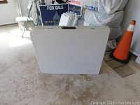 Folded 72 inch plastic top folding table standing upright with handle visible, showing dirt marks on surface.