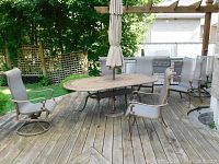 Six outdoor dining chairs around an oval patio table on a wooden deck, showing two swivel chairs at ends and four stationary chairs