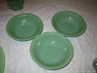 Three green glass salad bowls, about 7.5 inches each, with beaded edging around the rim shown on a white quilted surface.