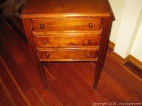 Front view of wooden sewing table with three drawers and wooden knob pulls
