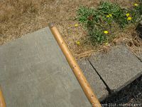 Close-up of the side and corner of the green steamer trunk showing worn paint and a wooden trim.