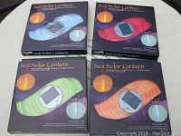 Four Sojo Solar Lanterns in original boxes, showing different colors and packaging design.