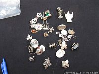 Lot of assorted mostly silver jewelry on black cloth including bird-shaped pendant, rings, cufflinks, pendants, showing wear.