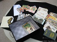 Overall lot with postcards, cards, books, and insignia displayed on a black cloth.