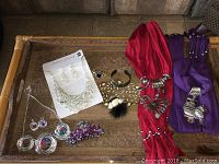 Overhead photo of scarfs and jewellery on a tray showing all items including scarfs, necklaces, earrings, brooches, bangle, and hair clip.