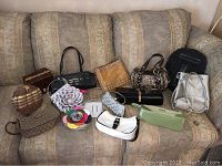 Full group shot of assorted purses including various styles such as woven, beaded, croc-embossed, buckle-trimmed, and floral appliqué on patterned couch.