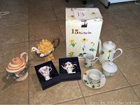 Full set showing cups, saucers, creamer, sugar bowl, large floral teapot, collectible teapots shaped like turtle and peacock, and two boxed night lights.