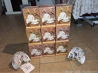 Nine boxed 50th Anniversary tea cup gift sets with three loose cups in front, two pink and one blue unboxed cups visible.