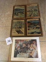 Shows four framed La Presse newspaper covers arranged on floor, barn wood frames, vintage French Canadian countryside artwork on covers.
