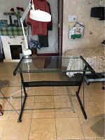Glass top desk with black metal frame showing slight bend in frame underneath.