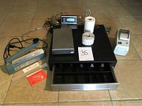 Cash drawer, Avery Berkeley scale platform, impulse sealer, rolls of labels and Zebra LP2824 label printer arranged on tile floor.