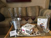 Wide shot showing champagne flutes on metal stand, ice bucket, martini glasses, decanter, and boxed glassware on table